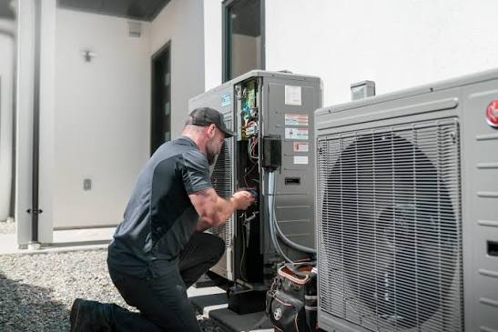 HVAC technician servicing paired outdoor cooling systems