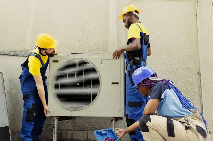 HVAC service team positioning residential cooling equipment