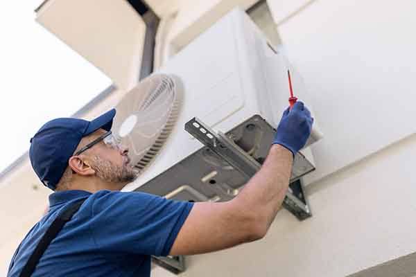 Technician testing a wall-mounted heating and cooling system