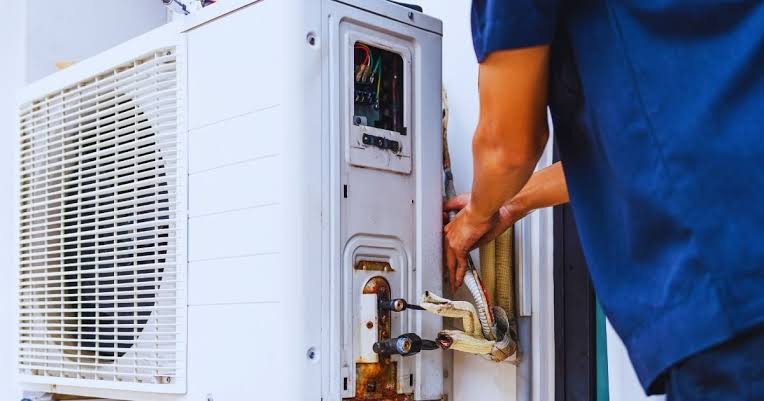 Technician connecting refrigerant lines during AC installation