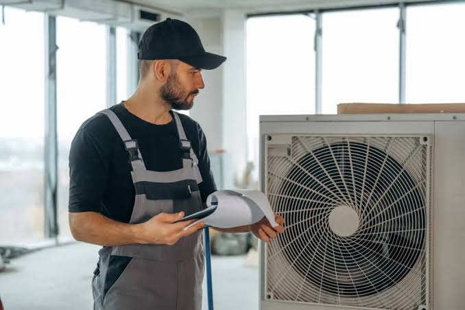 HVAC technician inspecting a modern condenser unit