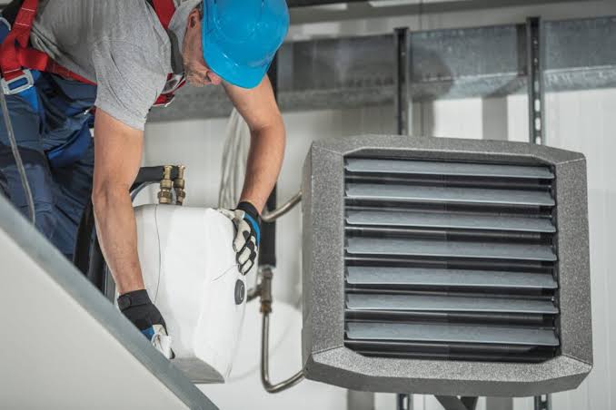 Technician servicing an indoor heating and cooling unit